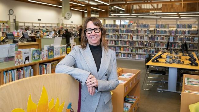Vailey Oehlke, director of the library, standing amongst book shelves