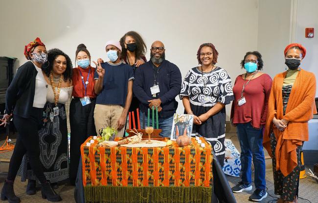 图书馆黑人文化倡导团队成员站在为宽扎节装饰的桌子后面。